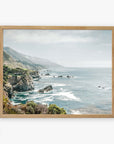 A framed archival photographic print depicting a serene coastal landscape along California Highway 1, with rocky cliffs and a vibrant blue ocean stretching into the distance under a hazy sky. The Big Sur Landscape Print by Offley Green captures the beauty of 'Rocky Rocks'.