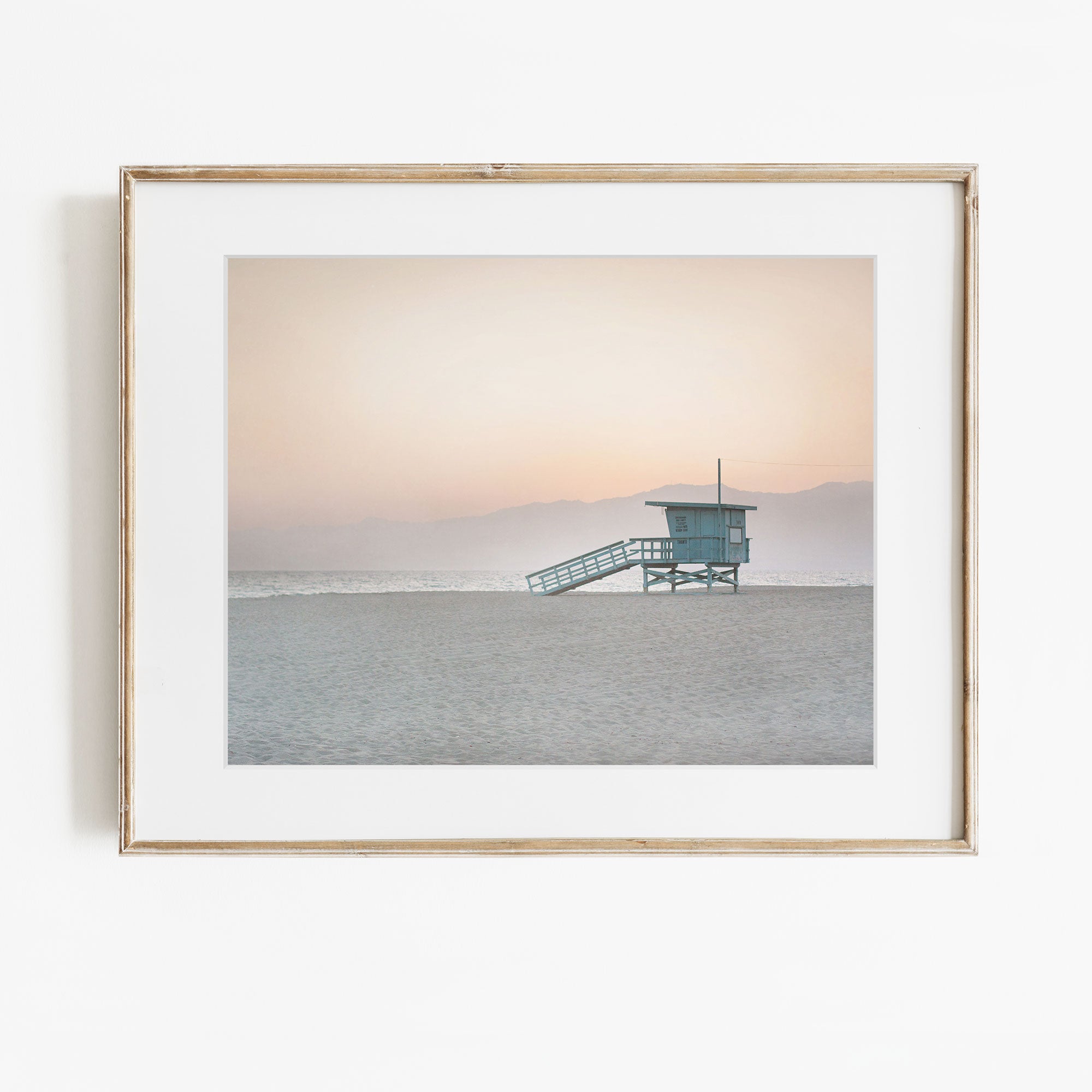Framed photograph of a lifeguard tower on a beach at sunset.