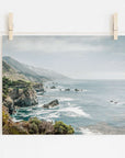A photo clipped to a line, displaying a scenic view of Offley Green's 'Rocky Rocks' landscape print of Big Sur's rugged coastline with cliffs and ocean, wrapped in a gentle mist, under a pale sky.