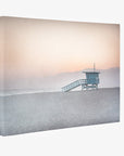 A Offley Green canvas print depicting a lifeguard tower on Venice Santa Monica beach during a snowy weather, with a soft pink sky and distant mountains in the background.